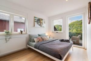 ein Schlafzimmer mit einem Bett und zwei Fenstern in der Unterkunft Luxus-Wellness-Haus am Waldsee in Rieden