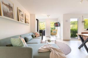 ein Wohnzimmer mit einem blauen Sofa und einem Tisch in der Unterkunft Luxus-Wellness-Haus am Waldsee in Rieden