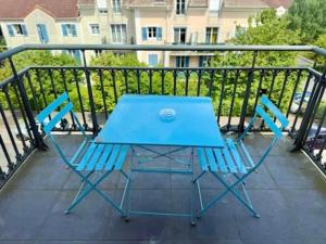 einen blauen Tisch und zwei Stühle auf dem Balkon in der Unterkunft Modern Blue - Disneyland Paris in Magny-le-Hongre