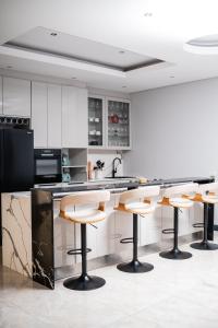 a kitchen with white cabinets and bar stools at Santareme Breeze in Sea Vista