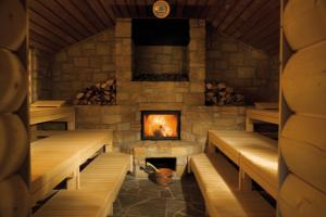 een stenen open haard in een kamer met banken en een vuur bij Strandhotel Dünenmeer - Adults only in Dierhagen