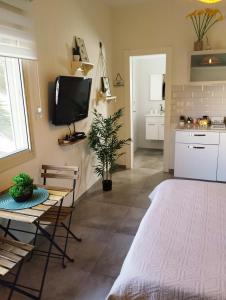 Una sala de estar con una mesa y un televisor en la pared. en Dekel Dom Baharava, en Beʼer Ora 14 fotos más