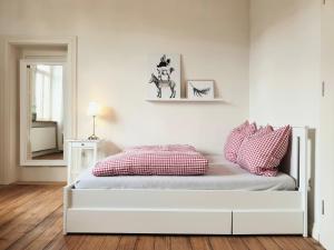 a white bedroom with a bed with red and white pillows at Bahnhof Grombach in Bad Rappenau