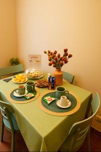 a table with a green table cloth with plates and cups at Marine Case Vacanze in Palermo