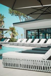 a row of white lounge chairs next to a swimming pool at Blue Studios by Comfort Suites in Golem