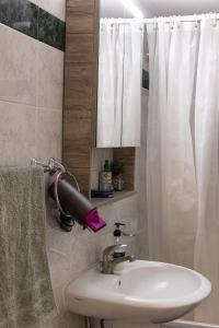 a bathroom with a sink and a blow dryer next to a shower at Comfort Zone - Spacious Apartment in Xanthi in Xanthi