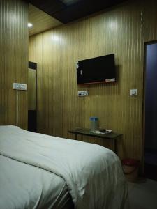 a bedroom with a bed and a tv on a wall at Manya hotel and dormitory in Jhānsi
