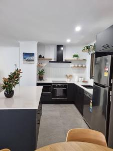 une cuisine avec des comptoirs noirs et blancs et un réfrigérateur dans l'établissement SeaEstaAtMoffatQuietbeachParklargefenced yard, à Caloundra