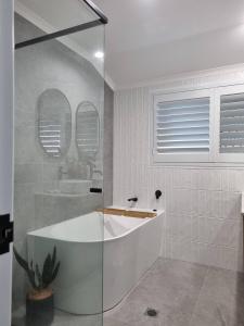 une salle de bain blanche avec une baignoire et un lavabo dans l'établissement SeaEstaAtMoffatQuietbeachParklargefenced yard, à Caloundra