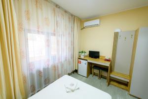 a room with a bed and a desk and a window at Pensiunea Domneasca in Piteşti