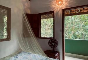 a bed with a mosquito net in a room with windows at Garden House in Ilha de Boipeba