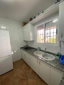 a white kitchen with a sink and a window at Las cuevas de María in Bácor