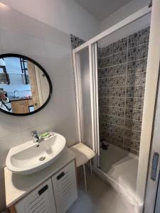 un bagno con lavandino, specchio e doccia di Loft marsa cube vue panoramique vue mer a La Marsa