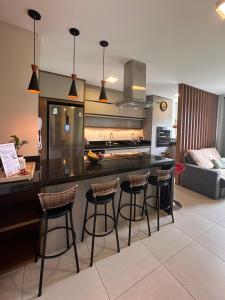 a kitchen with four bar stools and a counter in a room at Apto lindo e completo com piscina em Itajai in Itajaí