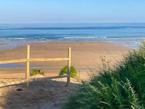 a wooden fence on a beach with the ocean at Bora House in Newquay