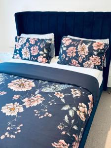 a bed with a blue headboard with floral sheets and pillows at Cozy Bedroom in a Townhouse Next to Jewellery Quarters and City Centre in Birmingham