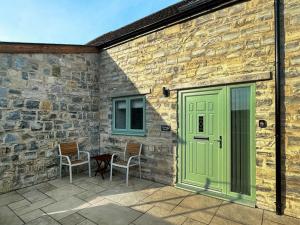 een terras met een groene deur en twee stoelen bij The Spud Shed - Uk47419 in Curry Mallet