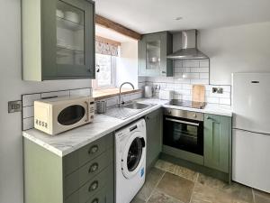 a kitchen with green cabinets and a microwave at The Spud Shed - Uk47419 in Curry Mallet