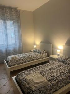 a bedroom with two beds and two lamps on tables at Humanitas, Forum center Milano Trilo with Terrazzo in Rozzano