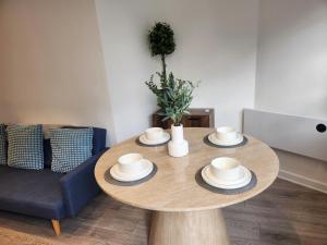a wooden table in a living room with a blue couch at Posyrooms Apartment in Stalybridge