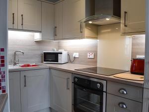a kitchen with white cabinets and a microwave at Causey Pike in Keswick