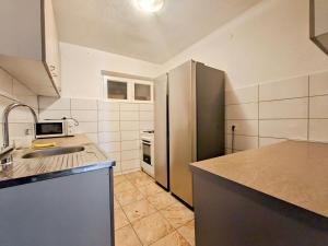 a kitchen with a sink and a refrigerator at Robinson Monte Cristo in Bogomolje