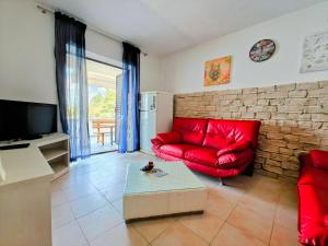 a living room with a red couch and a brick wall at Robinson Monte Cristo in Bogomolje