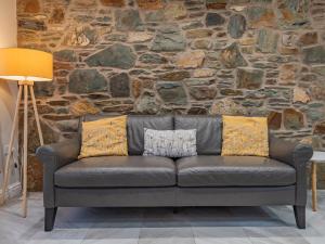 eine Ledercouch in einem Raum mit einer Steinwand in der Unterkunft Ty Cwtch in Holyhead