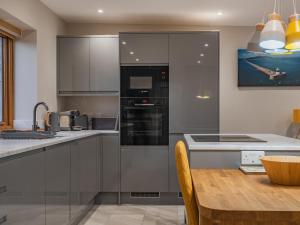 eine Küche mit Küchengeräten aus Edelstahl und einem Holztisch in der Unterkunft Ty Cwtch in Holyhead + 13 Fotos