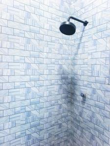 La salle de bains est pourvue d'une douche carrelée de blanc et d'une lumière. dans l'établissement Plaza Room Guest House, à Abrekuma