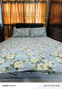 - un lit avec une couverture fleurie dans l'établissement Plaza Room Guest House, à Abrekuma