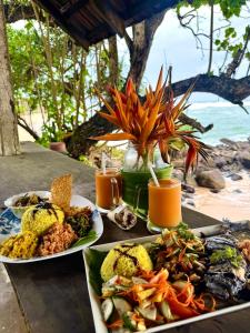 a table with two plates of food and drinks at Sooriya villa in Unawatuna