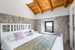 a bedroom with a white bed and a stone wall at Luciana by Vintage Travel in Mihanići