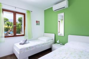 two beds in a room with green walls and a window at Sele by Vintage Travel in Gruda +28 photos