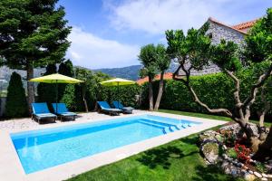 a pool with chairs and umbrellas in a yard at Sele by Vintage Travel in Dubrovnik