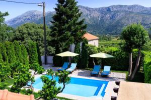 a swimming pool with chairs and umbrellas and mountains at Sele by Vintage Travel in Gruda