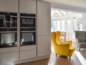 a living room with a yellow chair and a kitchen at Pines Cottage - Uk42110 in St Margarets at Cliff +2 photos