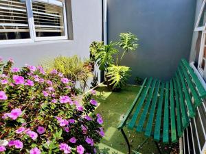 a green bench sitting next to some pink flowers at White Pearl at Strand in Strand