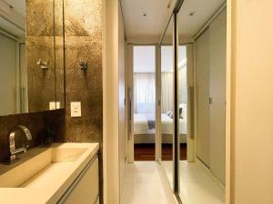 a bathroom with a sink and a mirror and a bedroom at Brisas do Cabo Branco by Hosppedar in Tambaú +43 photos