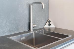 eine Küchenspüle aus Edelstahl mit einem Wasserhahn in der Unterkunft Luxury Beachfront Villa 4p - Uitzicht op de Baai & Duinen - Villa 19 in Ouddorp + 28 Fotos