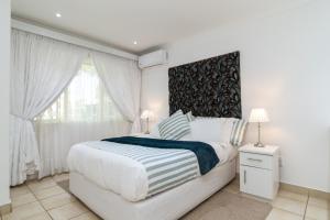 a white bedroom with a large bed and a window at Jacqueline Drive 51 in Ballito +31 photos