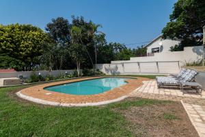 a swimming pool in a yard with two chairs and a table at Jacqueline Drive 51 in Ballito