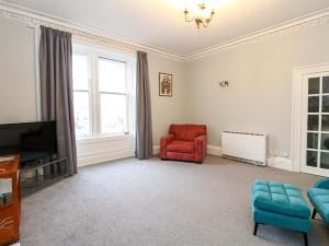a living room with a red chair and a tv at 9A Market Square in Stonehaven +12 photos