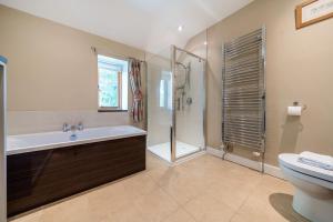 a bathroom with a tub and a shower and a toilet at Orchard House 140 in Blakeney +28 photos