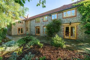 an exterior view of a large stone house at Orchard House 140 in Blakeney