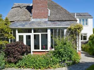a house with a conservatory with a thatched roof at Swiss Cottage in Chideock
