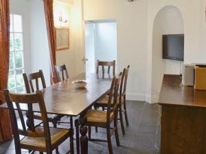 a dining room with a wooden table and chairs at Swiss Cottage in Chideock +5 photos