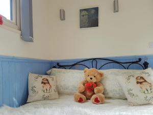 a teddy bear sitting on a bed with pillows at The Shepherd's Hut in Herstmonceux +22 photos