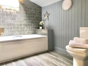 a bathroom with a bath tub and a toilet at Lightfoot House in Redmire +7 photos