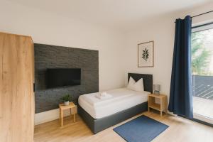 1 dormitorio con 1 cama y TV en una pared de ladrillo en SUNNYHOME Monteurwohnungen und Apartments in Bodenwöhr, en Bodenwöhr